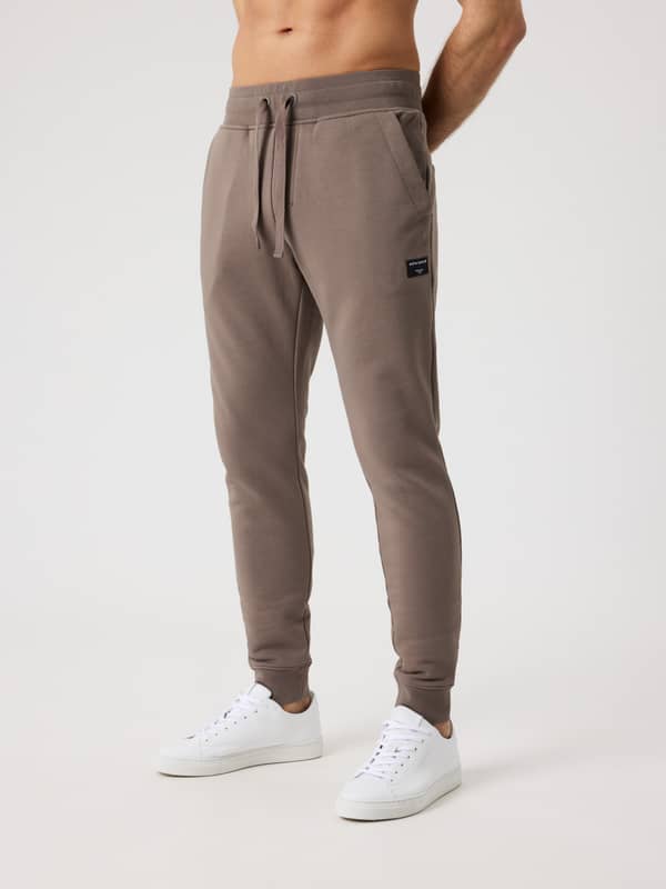 Vue de face d'un homme portant le Centre Tapered Sweatpants en Falcon (Marron), avec une coupe ajustée et fuselée.