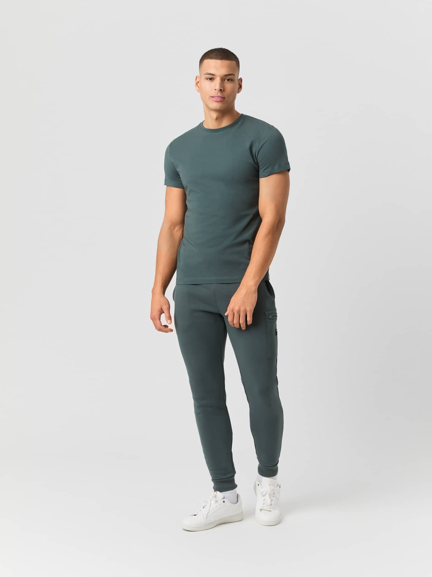 Full body shot of a model wearing the green Björn Borg Centre T-shirt with matching joggers and white sneakers. - Image 3