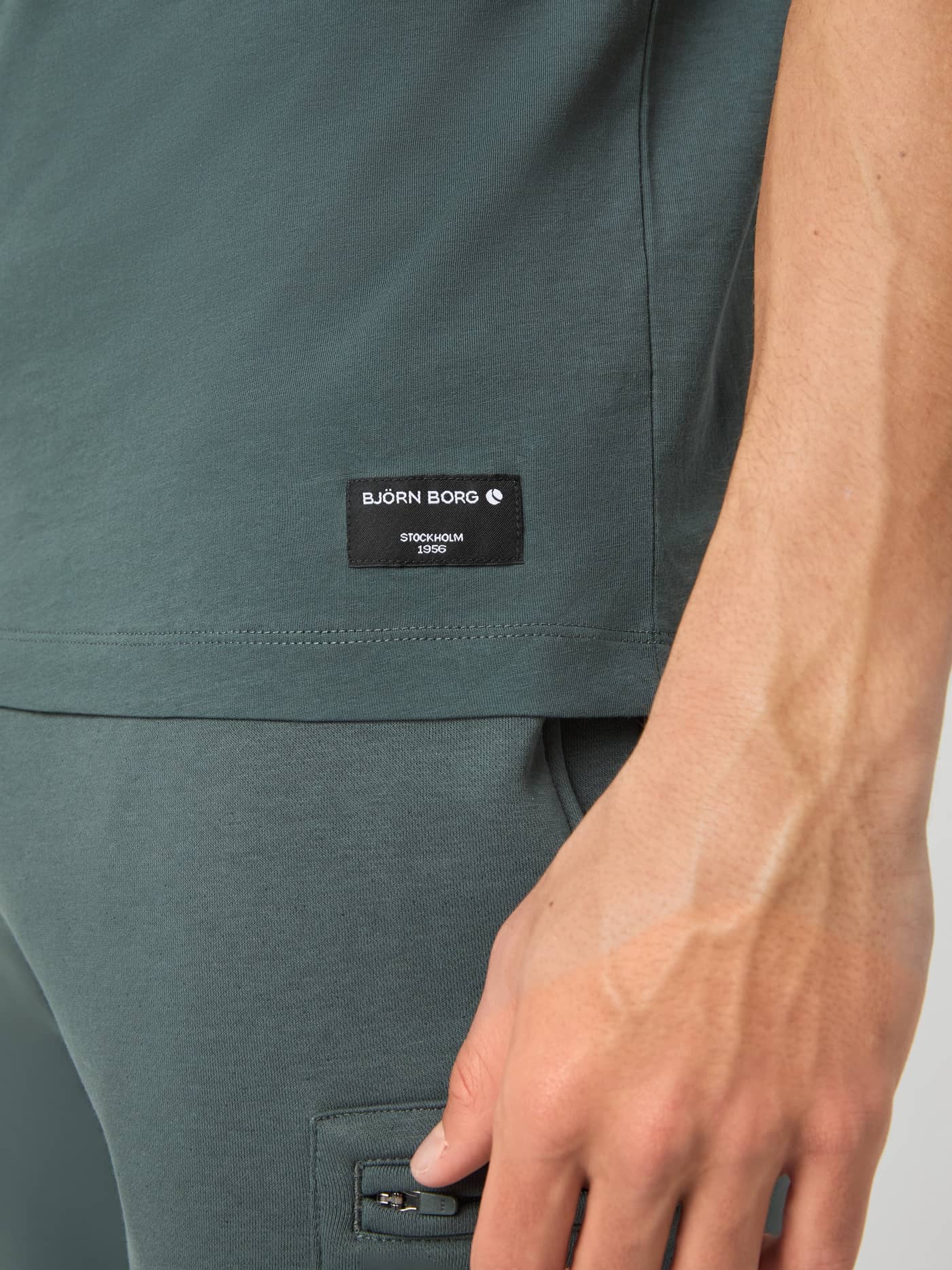 Close-up of the Björn Borg Centre T-shirt in Urban Chic green, showing the black branded label at the hem. - Image 5