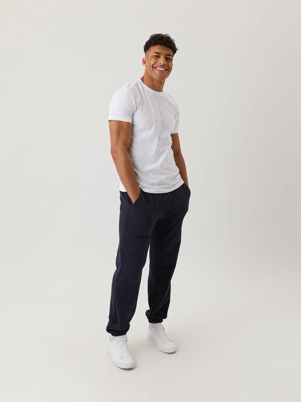 Mannequin portant le Centre T-Shirt en Brilliant White (Blanc) avec pantalon de survêtement sombre et baskets blanches. - Image 8