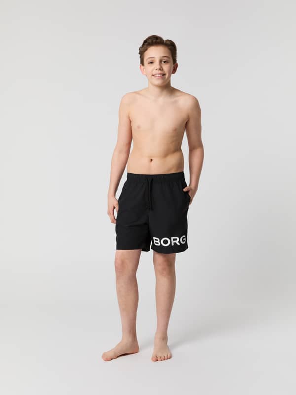Borg Swim Shorts til børn i Black Beauty (Sort) set forfra i fuld figur med hvidt logo til svømning.
