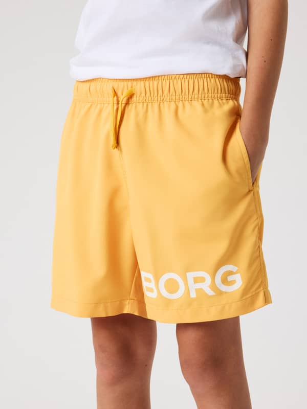 Borg Swim Shorts til børn i Marigold (Gul) set forfra med hvidt logo og almindelig pasform.