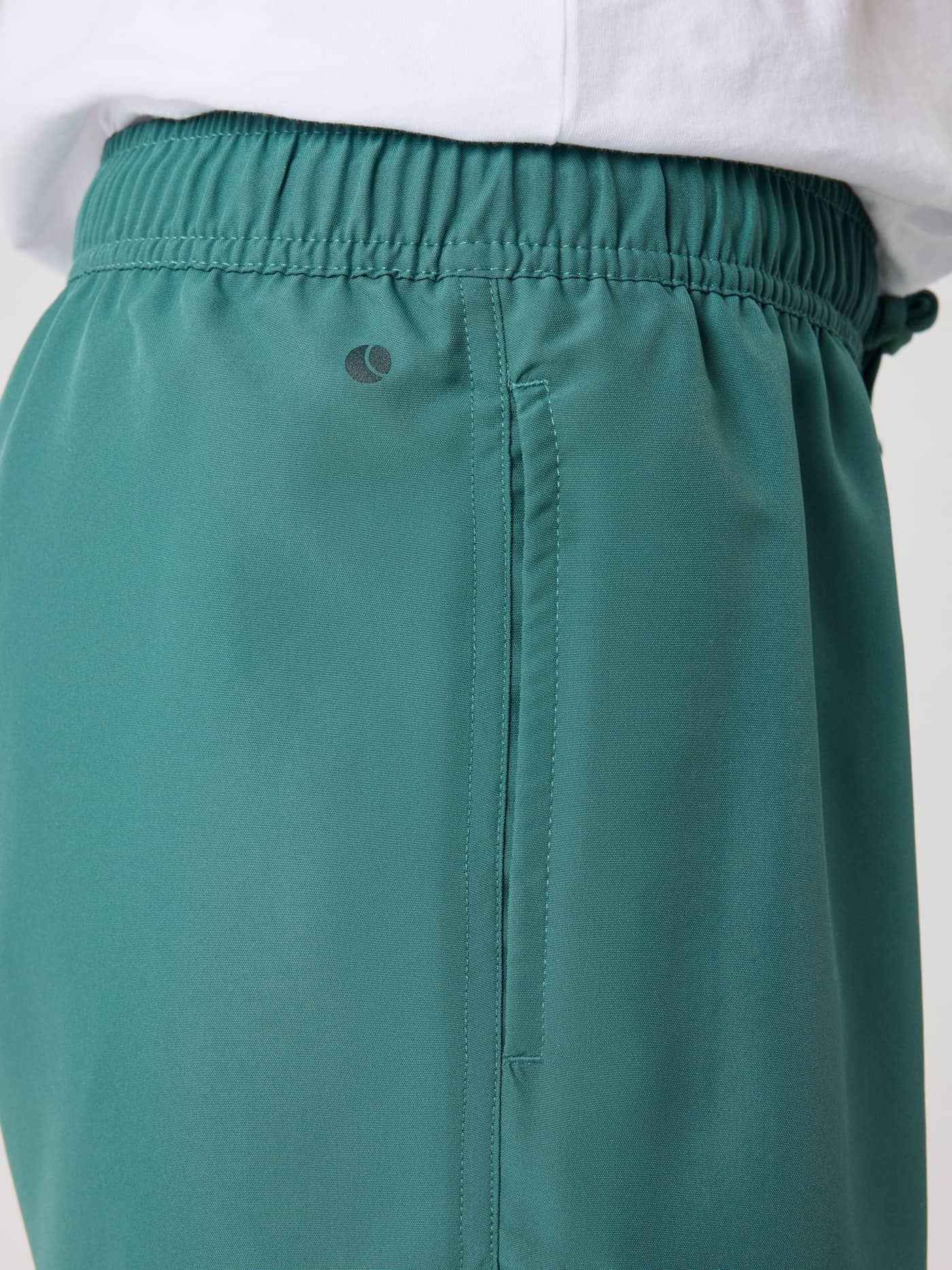 Detailed side view of the kids' Borg Swim Shorts in Blue Spruce (Green), showing the waistband, pocket, and dark logo. - Image 4