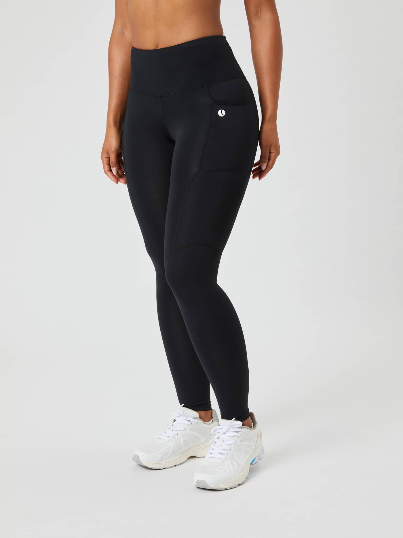 Framifrån på en modell i Ace Pocket Tights i Black Beauty (Svart) med hög midja och en vit tennislogotyp. - Image 2