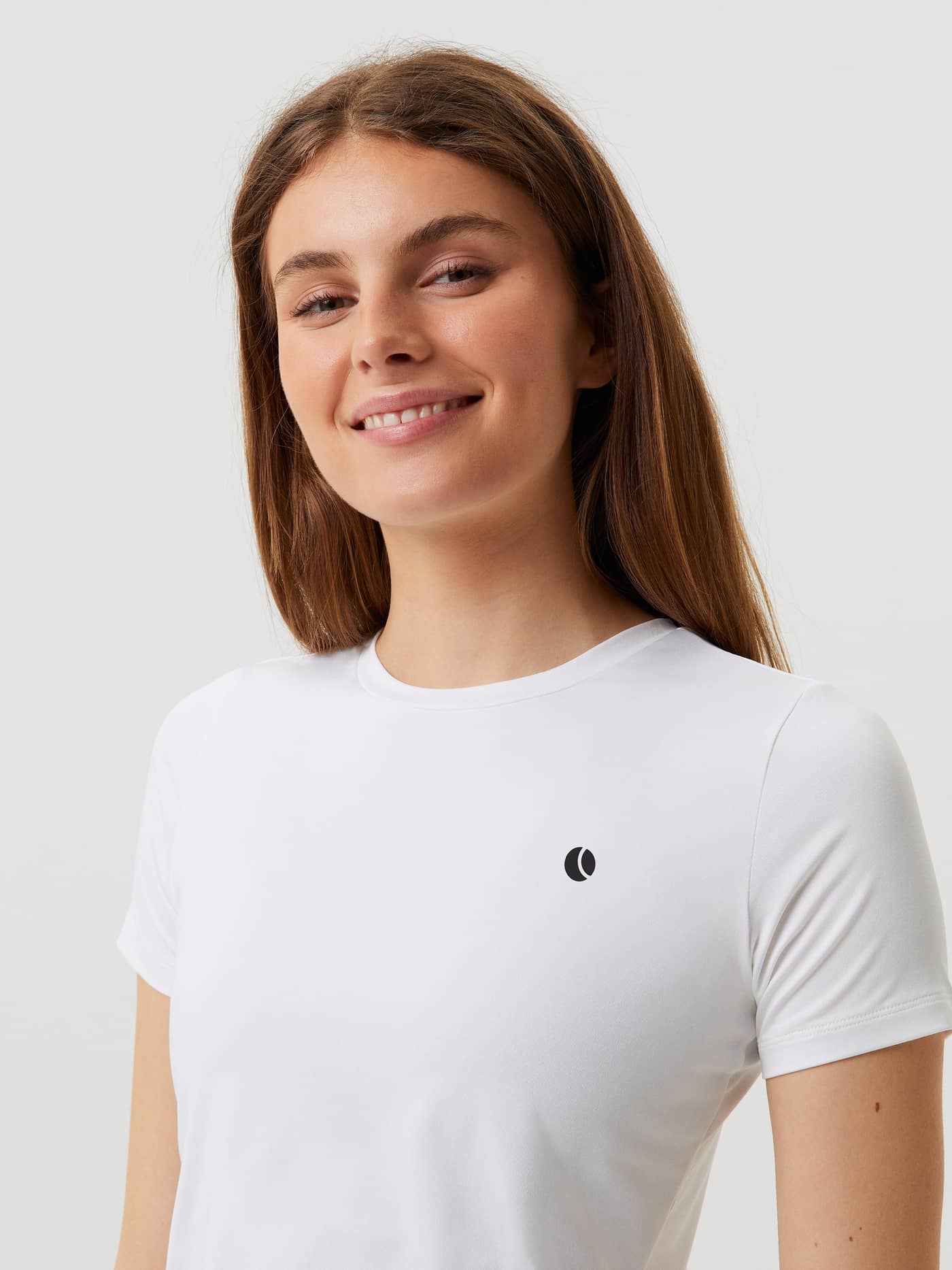 Gros plan d'une femme souriante portant le Ace Slim T-Shirt Brilliant White (Blanc) au logo de tennis noir. - Image 3