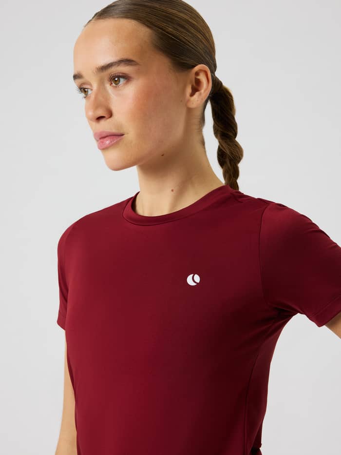 Close-up van het Ace Slim T-Shirt in Cabernet (rood) met een ronde hals en wit tennislogo.
