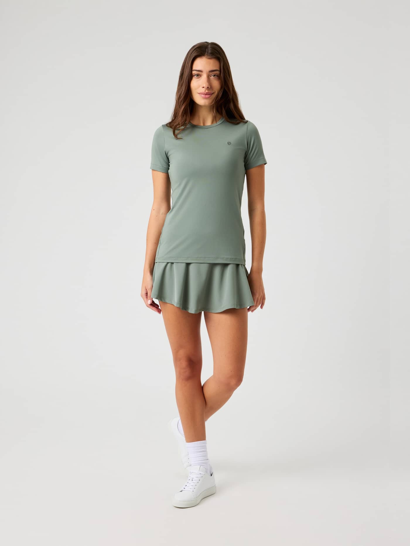 Front view of a model wearing the Björn Borg Ace Slim T-Shirt in Agave Green, styled with a matching tennis skirt. - Image 4