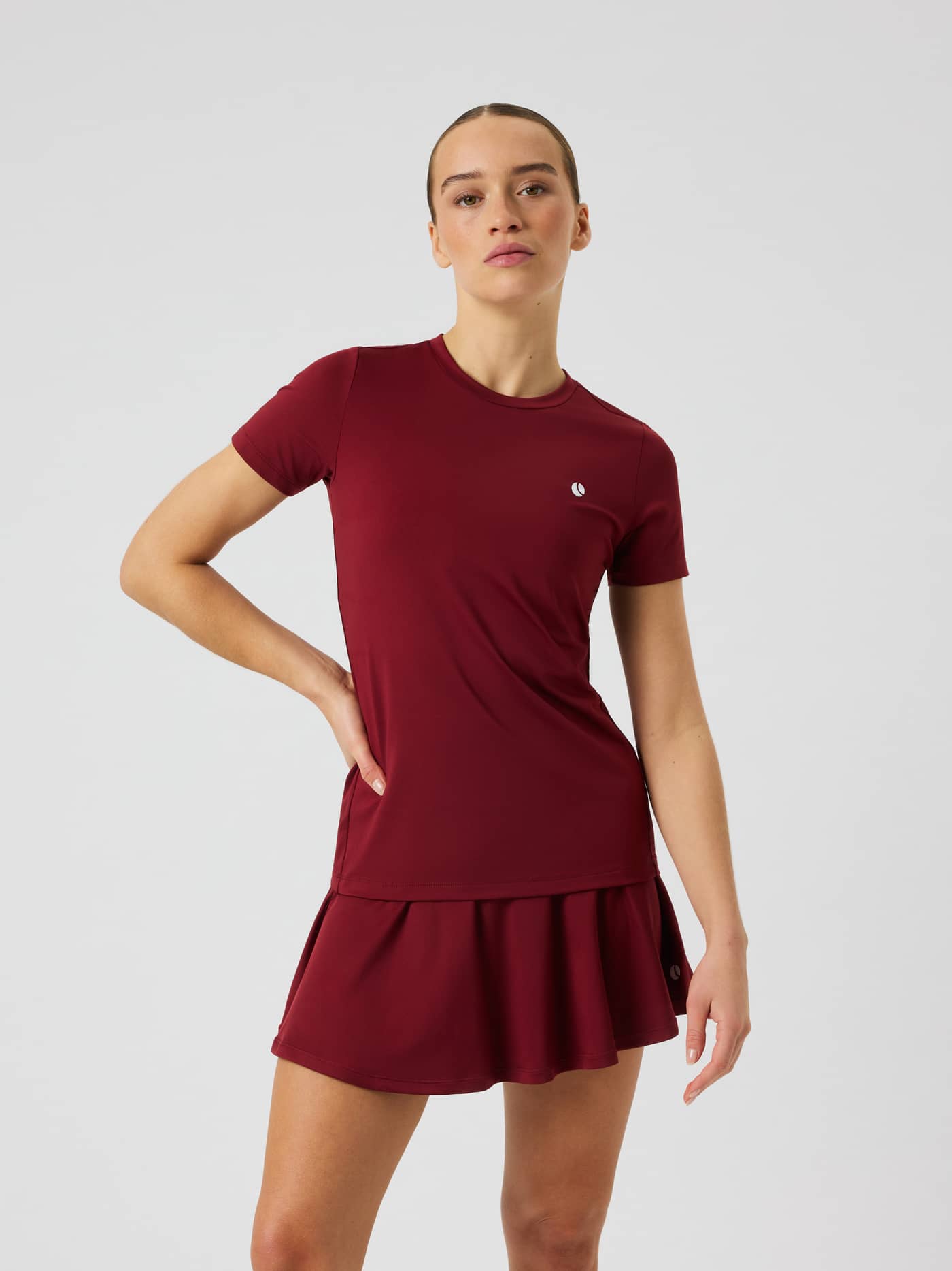 Vooraanzicht van het Ace Slim T-Shirt in Cabernet (Rood) met korte mouwen, een slim fit pasvorm en een wit tennislogo. - Image 1
