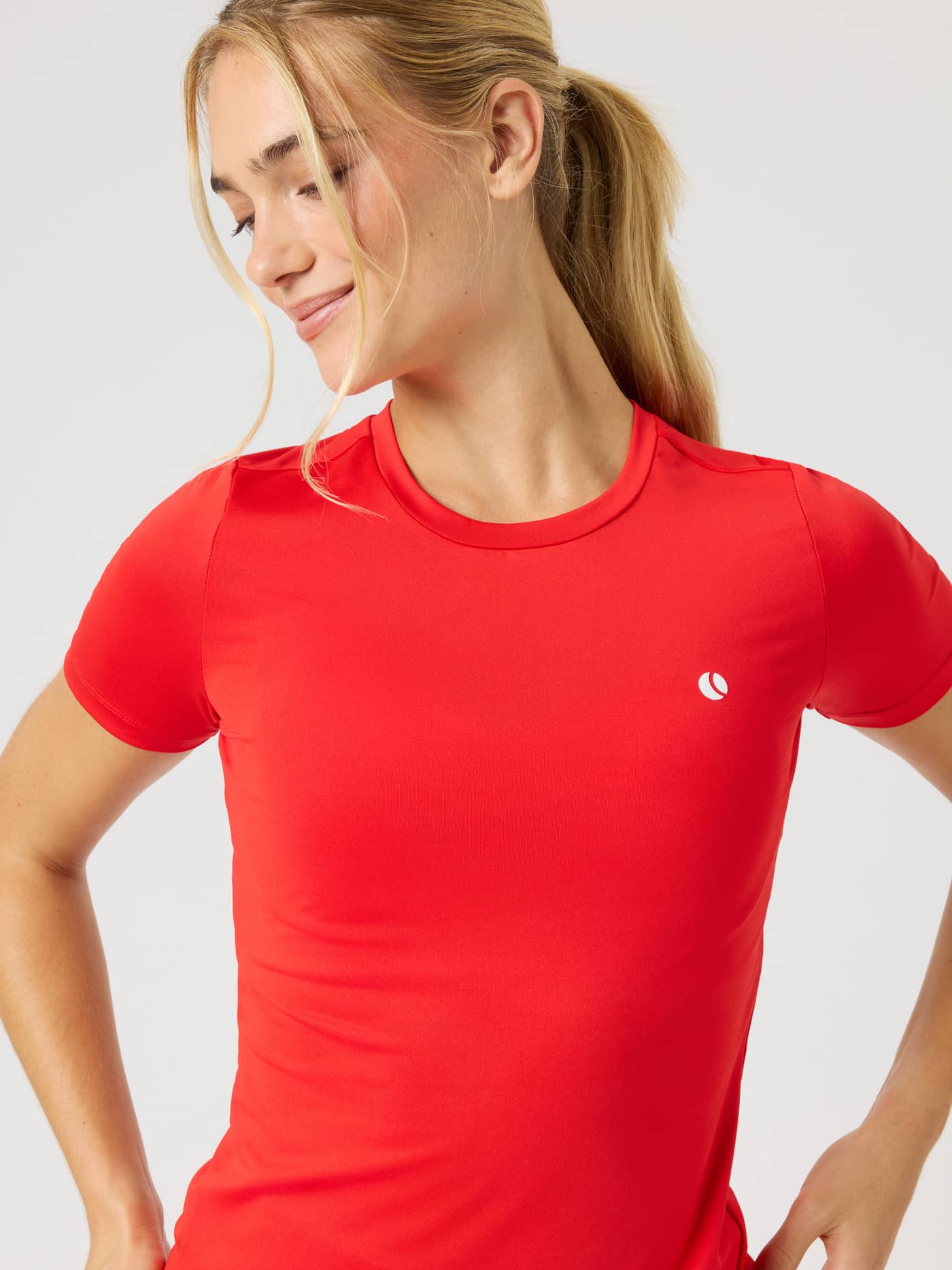 Model wearing the Ace Slim T-Shirt in Flame Scarlet (Red) with a white tennis ball logo and slim fit for on-court training. - Image 4