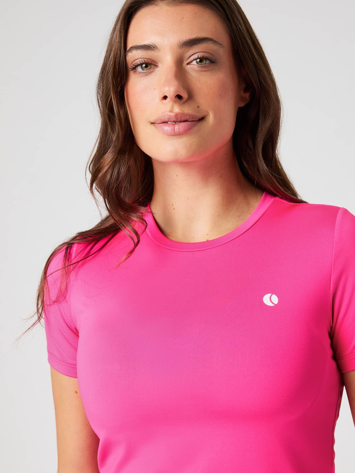 Close-up of a woman wearing the Björn Borg Ace Slim T-Shirt in Pink Glo, showing the round neckline and logo detail. - Image 4