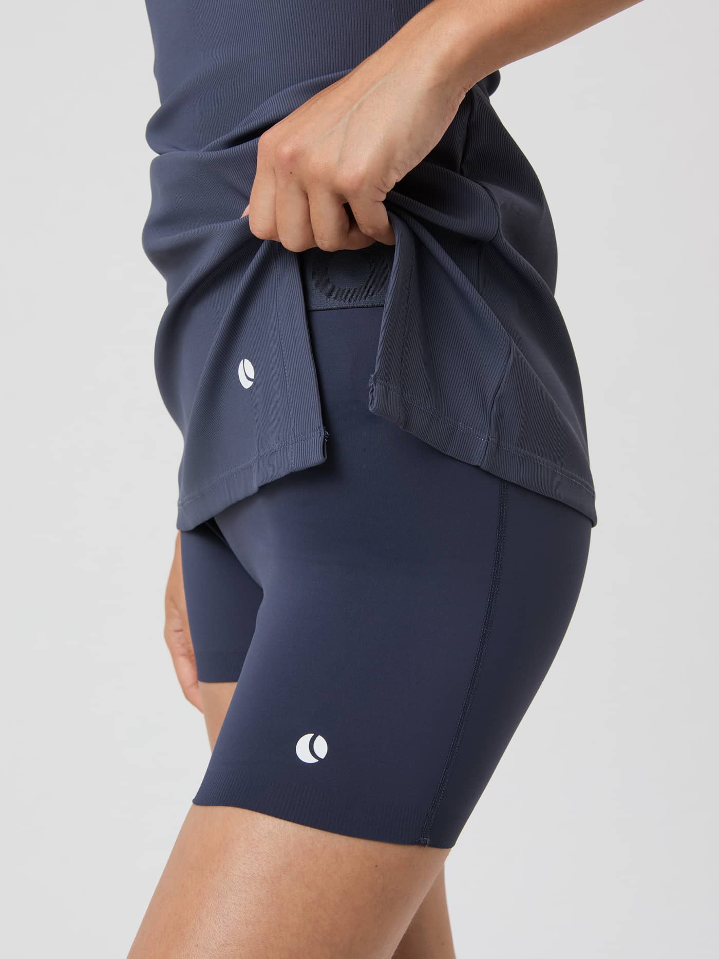 Detailed close-up of the Ace Ribbed Dress in Odyssey Gray (Grey), featuring the side slit and white tennis ball logo. - Image 4