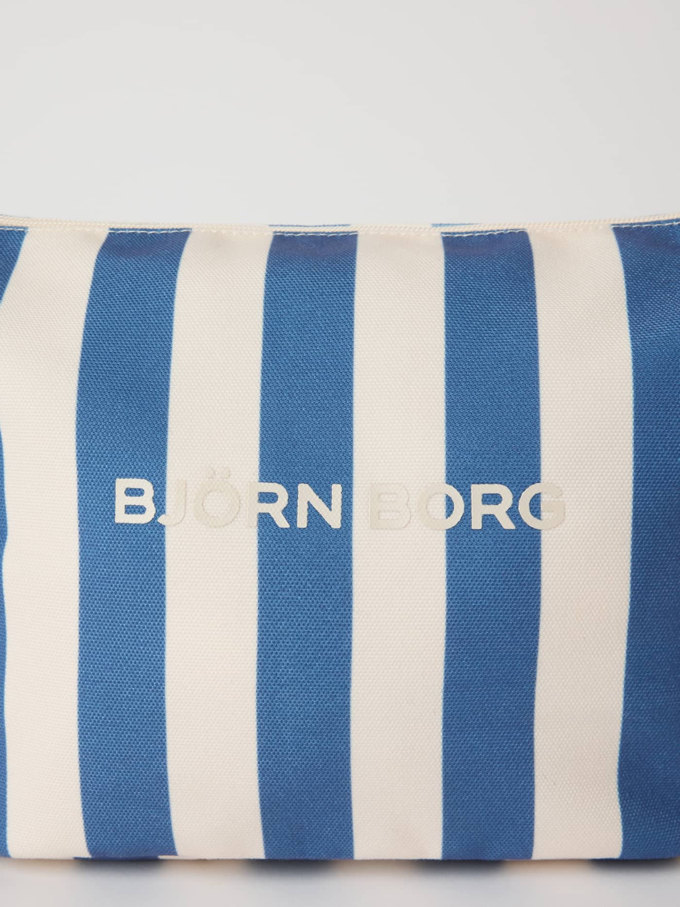 Gros plan sur la trousse de toilette Borg Beach Wash Bag en Coastal Fjord (Bleu) avec rayures et logo blancs. - Image 3