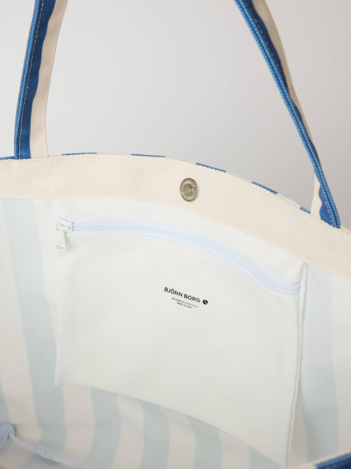 Vue intérieure du Borg Beach Tote M - 27L rayé en Coastal Fjord (Bleu) avec un logo noir sur la poche intérieure zippée. - Image 4