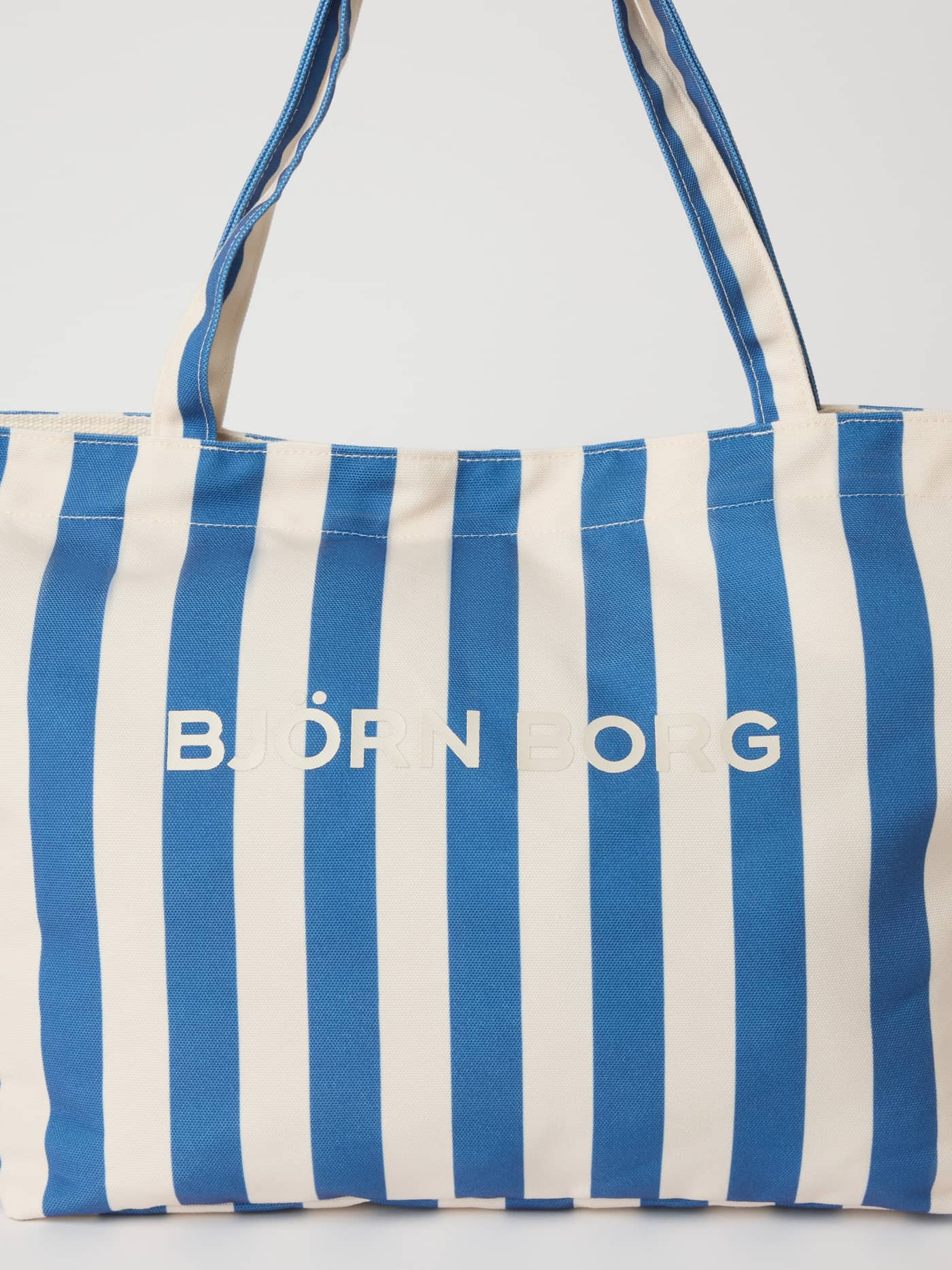 Vue de face du Borg Beach Tote M - 27L à rayures en Coastal Fjord (Bleu) avec un logo blanc. - Image 3