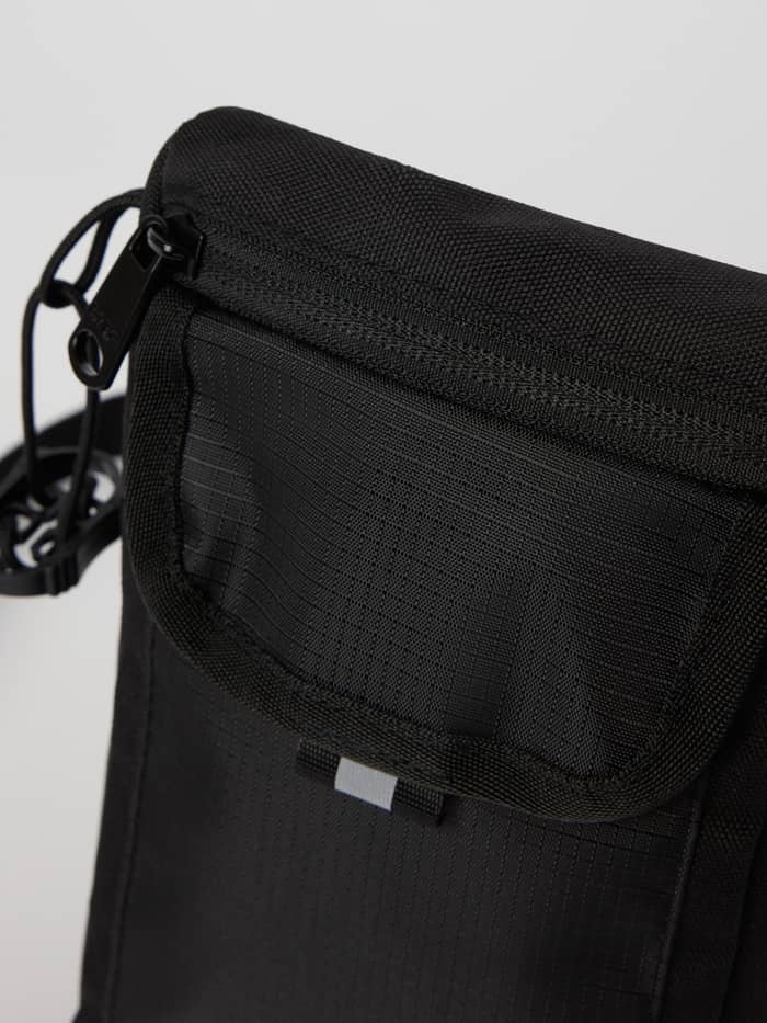 Detailed close-up of the Björn Borg Crossover Bag S in Black Beauty (Black), highlighting its durable material and zipper. - Image 4