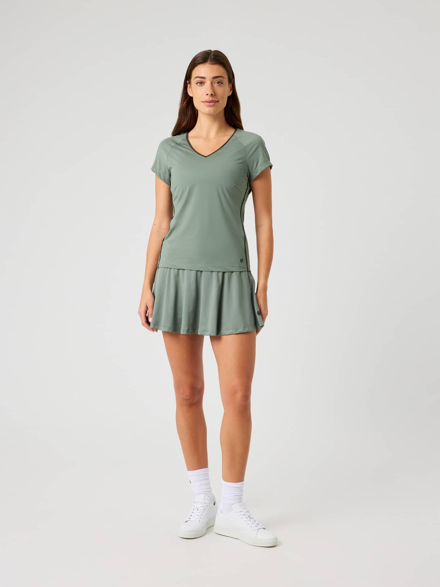 Front view of a woman wearing the Björn Borg Ace Jersey Skirt in agave green with a matching top. - Image 3