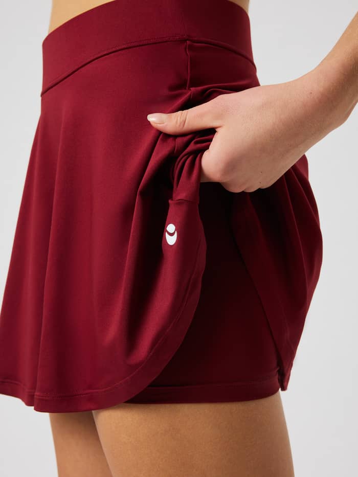 Close-up Ace Jersey Skirt in Cabernet (rood) met binnenbroek en wit logo voor tennis.