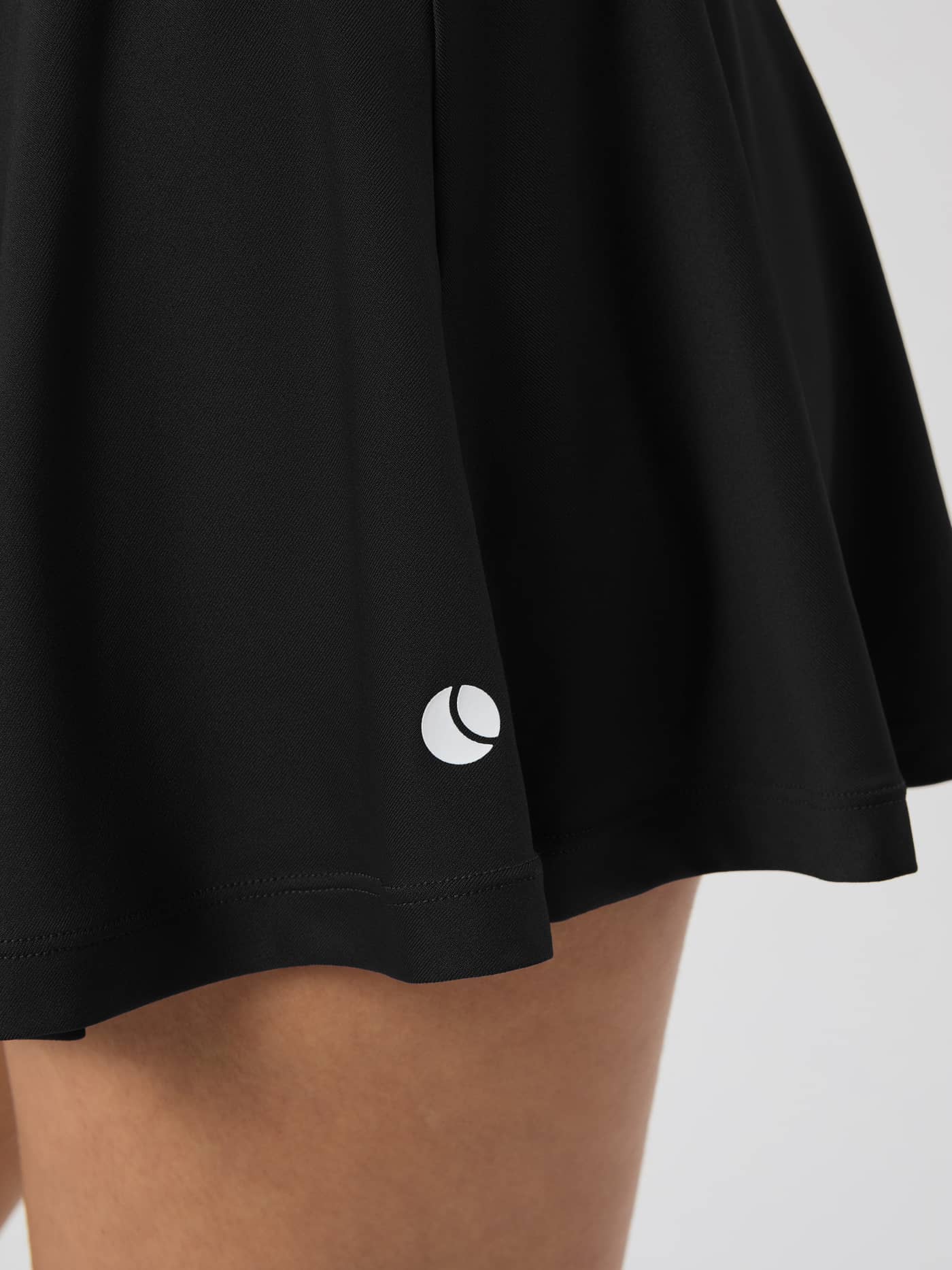 Détail de la Ace Jersey Skirt en Black Beauty (Noir) en tissu côtelé avec logo de tennis blanc sur l'ourlet. - Image 4