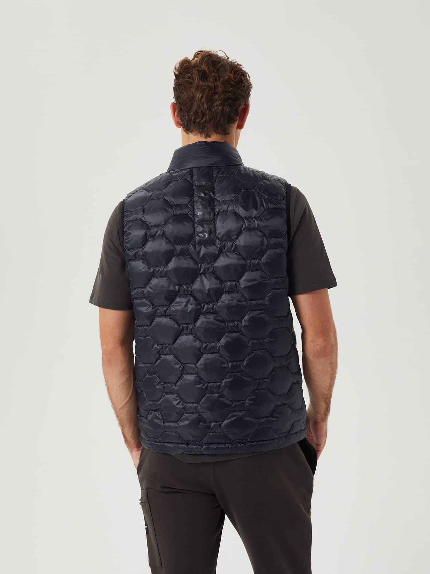 Achteraanzicht van een man in het gewatteerde Borg Down Liner Vest in Black Beauty (Zwart) met een tonale logostreep. - Image 3
