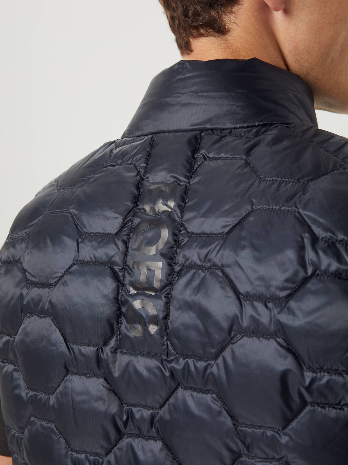 Achteraanzicht van functioneel Borg Down Liner Vest in Black Beauty (Zwart) met hexagonaal gewatteerd patroon en zwart logo. - Image 5