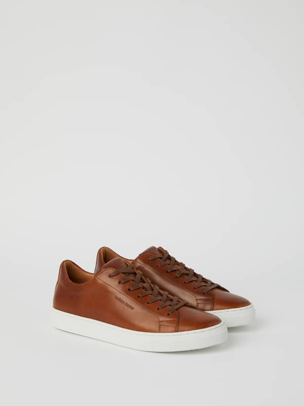 Vue de trois-quarts des Men’s Classic Leather sneakers en cuir marron, semelles blanches et style tennis minimaliste.