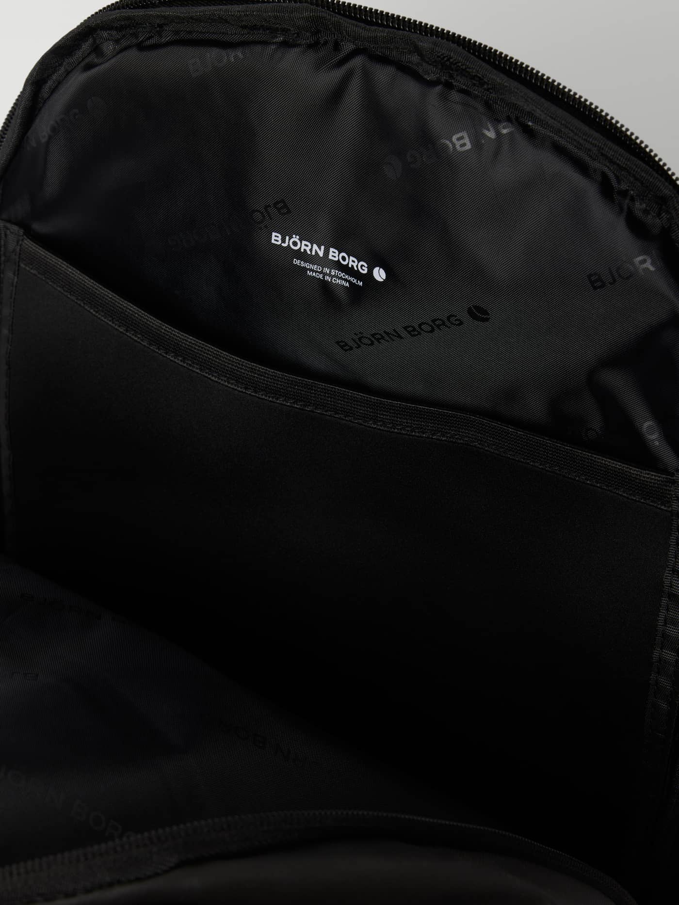 Innenansicht des Core Coated Iconic Backpack 26L in Black Beauty (Schwarz) mit Marken-Logoprint-Futter. - Image 3