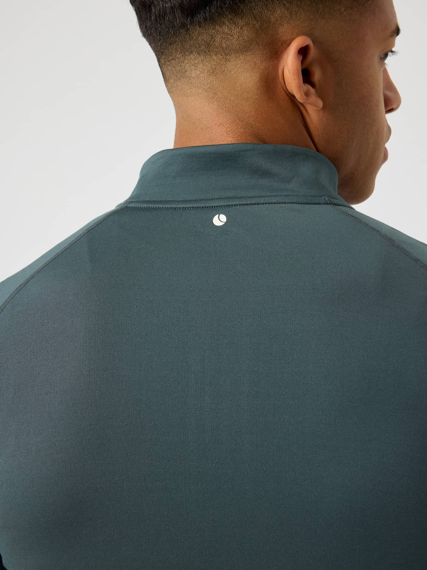 Back view of a man in the Urban Chic (Green) Borg Midlayer Half Zip, featuring a white tennis ball logo for training. - Image 4