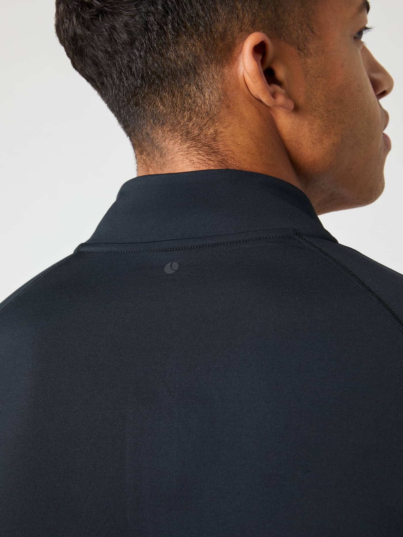 Close-up detail shot of the back of a model wearing the black Borg Midlayer Half Zip, focusing on the high mock neck collar. - Image 5