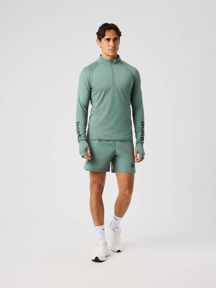 Front view of the Borg Midlayer Half Zip in laurel wreath (green) with a half-zip and black logo prints for training.