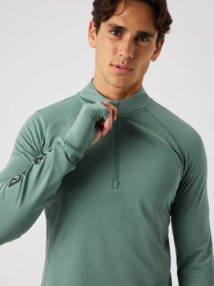 Male model wearing the Borg Midlayer Half Zip in laurel wreath (green) for training, showing the half-zip and thumb holes.