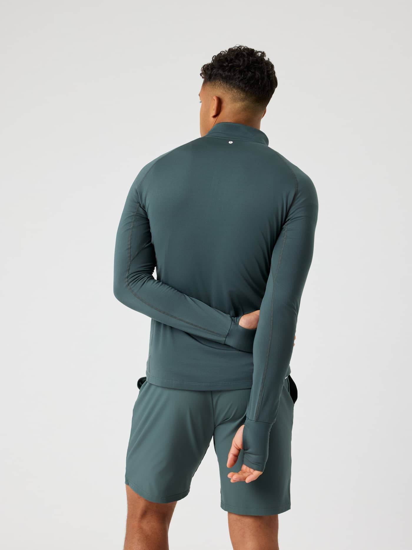 Back view of a man wearing the Urban Chic (Green) Borg Midlayer Half Zip with thumb hole openings for training. - Image 2