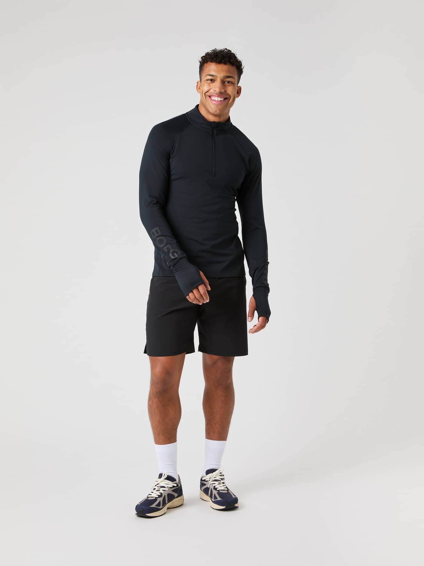 Full body shot of a man wearing the black Björn Borg Midlayer Half Zip and black shorts. - Image 4
