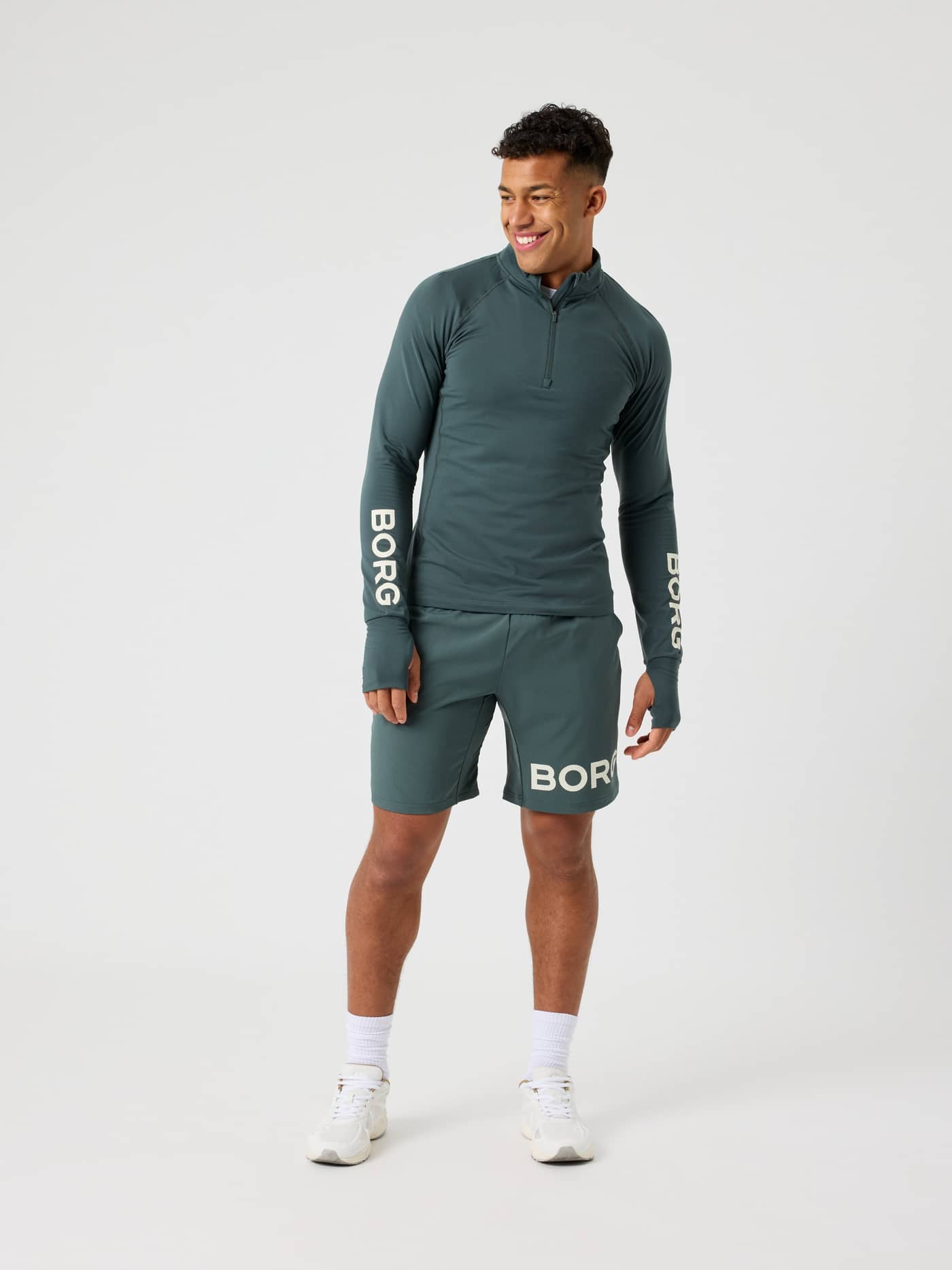 Full-body front view of a man wearing the Urban Chic (Green) Björn Borg Midlayer Half Zip for training with white logos. - Image 3