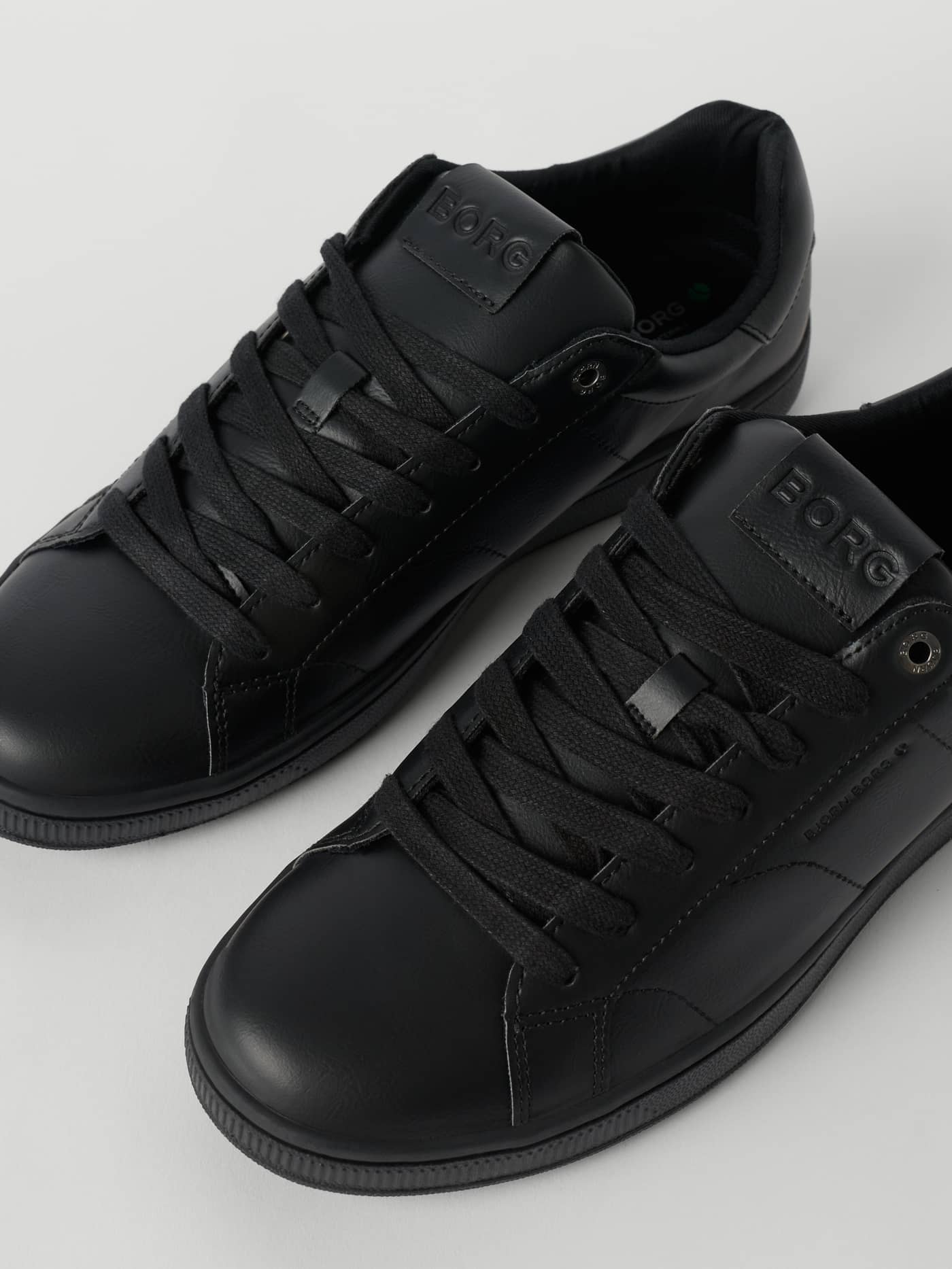 Närbild på Men's Deuce Sneakers i svart med en tennisdesign i syntetläder och ton-i-ton BORG-logotyper. - Image 2