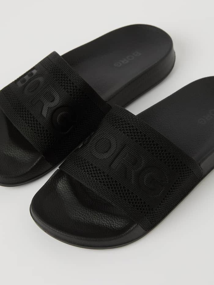 Close-up van de zwarte Womens Sandal Knox Knit met een zacht gebreid bovenwerk en een tonaal Borg-logo. - Image 2