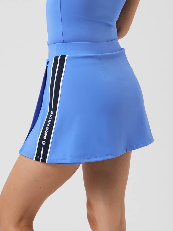 Zijaanzicht van de Björn Borg Ace Stretch Skirt in Ultramarine (Blauw) met een witte logostreep voor tennis. - Image 3