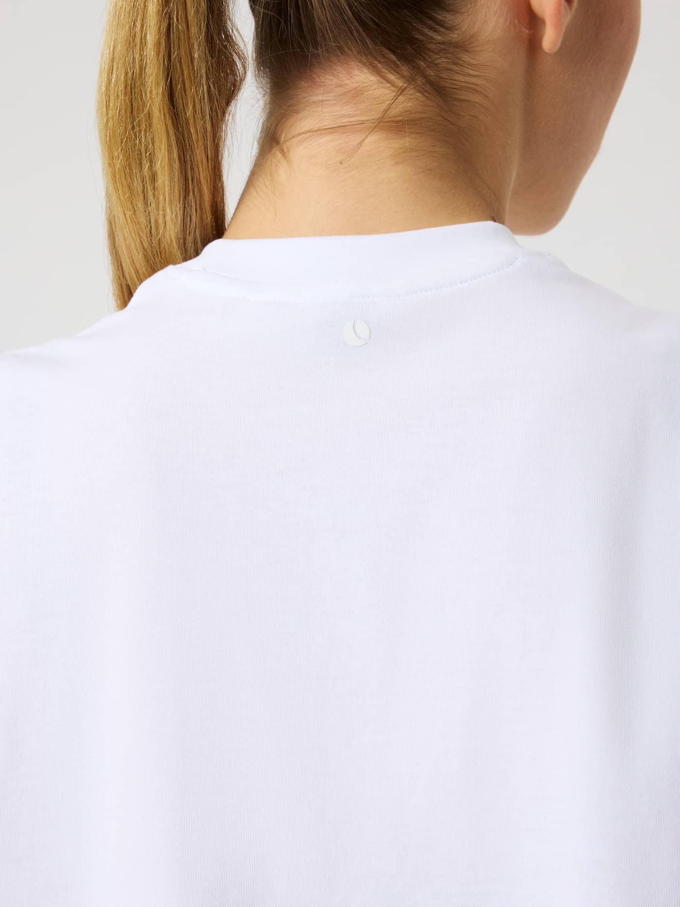 Back view close-up of the Studio Oversized Cropped T-Shirt in Brilliant White (White) with a white logo for training. - Image 4