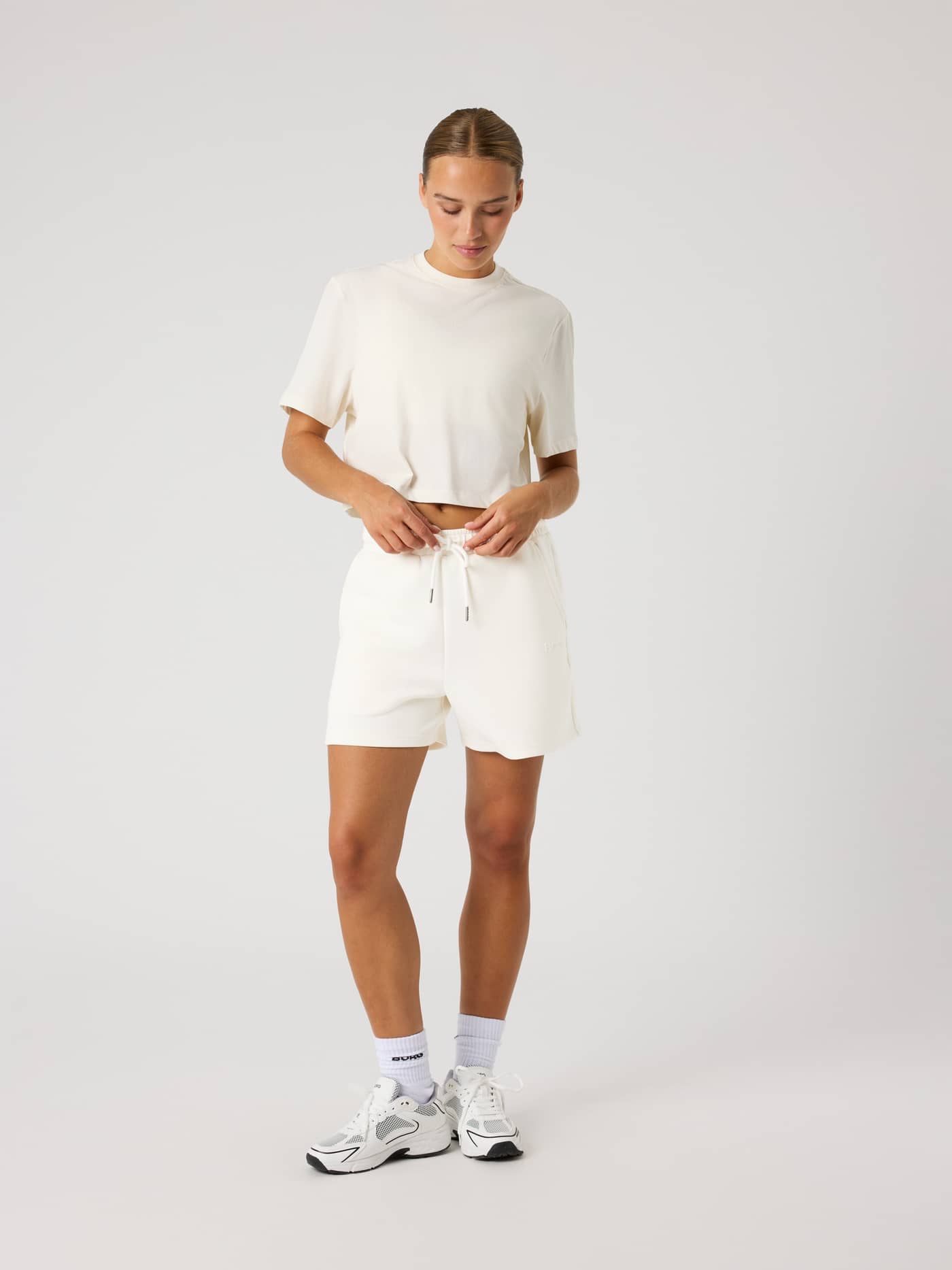 Vue de face d'une femme portant le Studio Oversized Cropped T-Shirt en Tofu (Blanc) pour l'entraînement. - Image 3