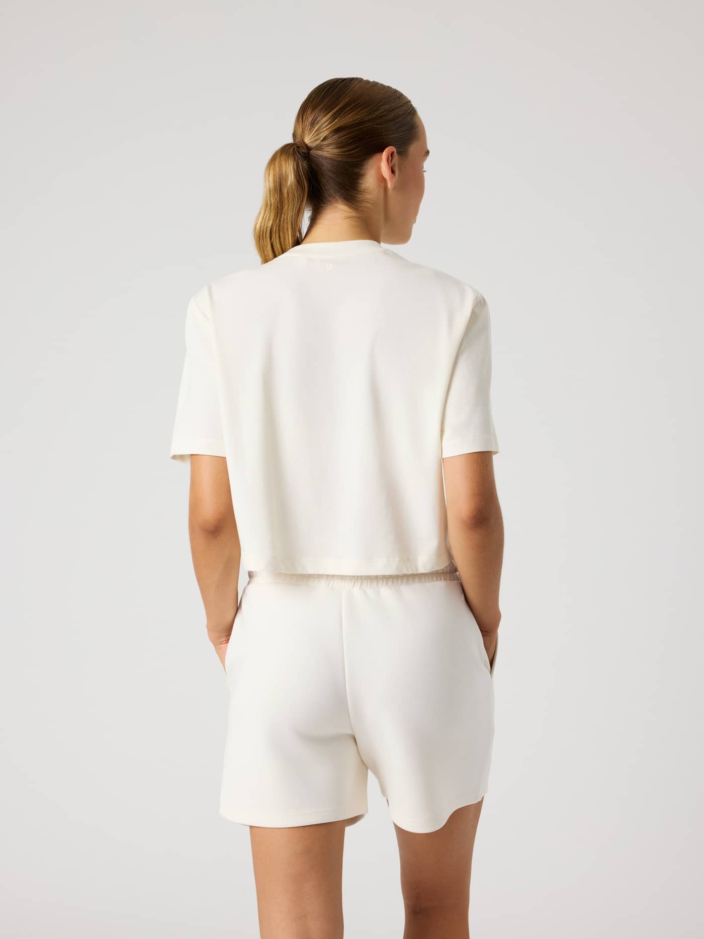 Vue de dos d'un mannequin portant le Studio Oversized Cropped T-Shirt en Tofu (Blanc), coupe d'entraînement décontractée. - Image 2