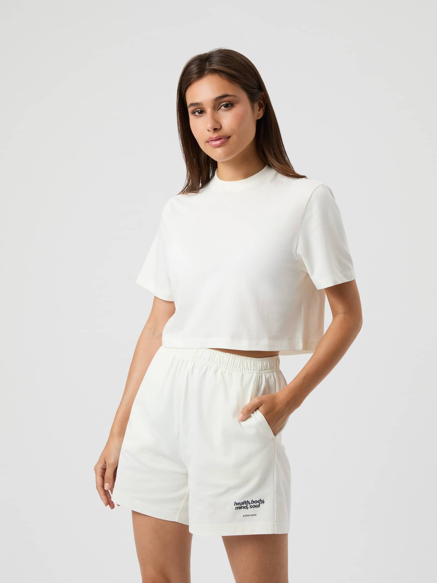 Vue de face d'une femme portant le Studio Oversized Cropped T-Shirt en coton Cannoli Cream (Blanc) pour l'entraînement. - Image 1