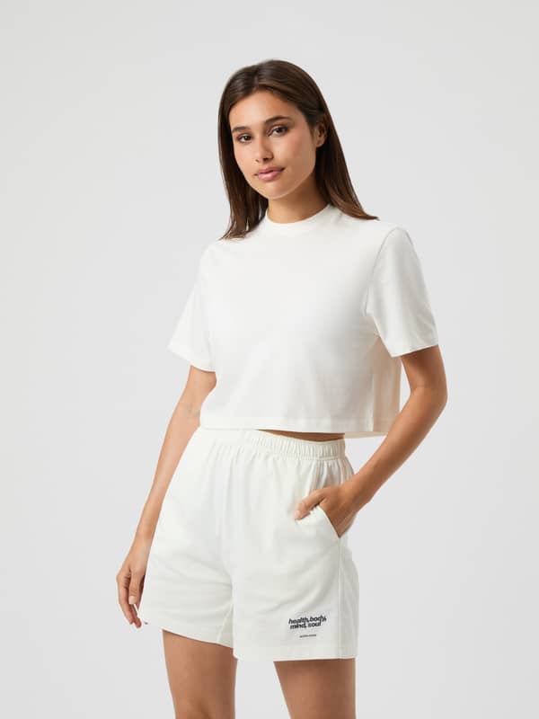 Front view of a woman wearing the cotton Björn Borg Studio Oversized Cropped T-Shirt in Cannoli Cream (White) for training.