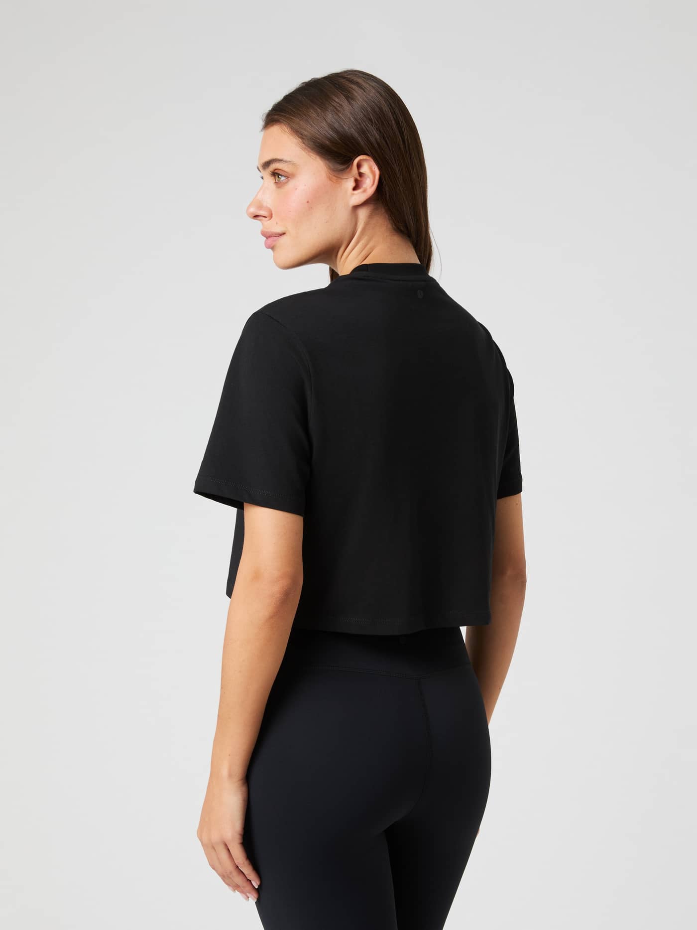 Back view of a woman wearing the cotton Björn Borg Studio Oversized Cropped T-Shirt in Black Beauty (Black) for training. - Image 2