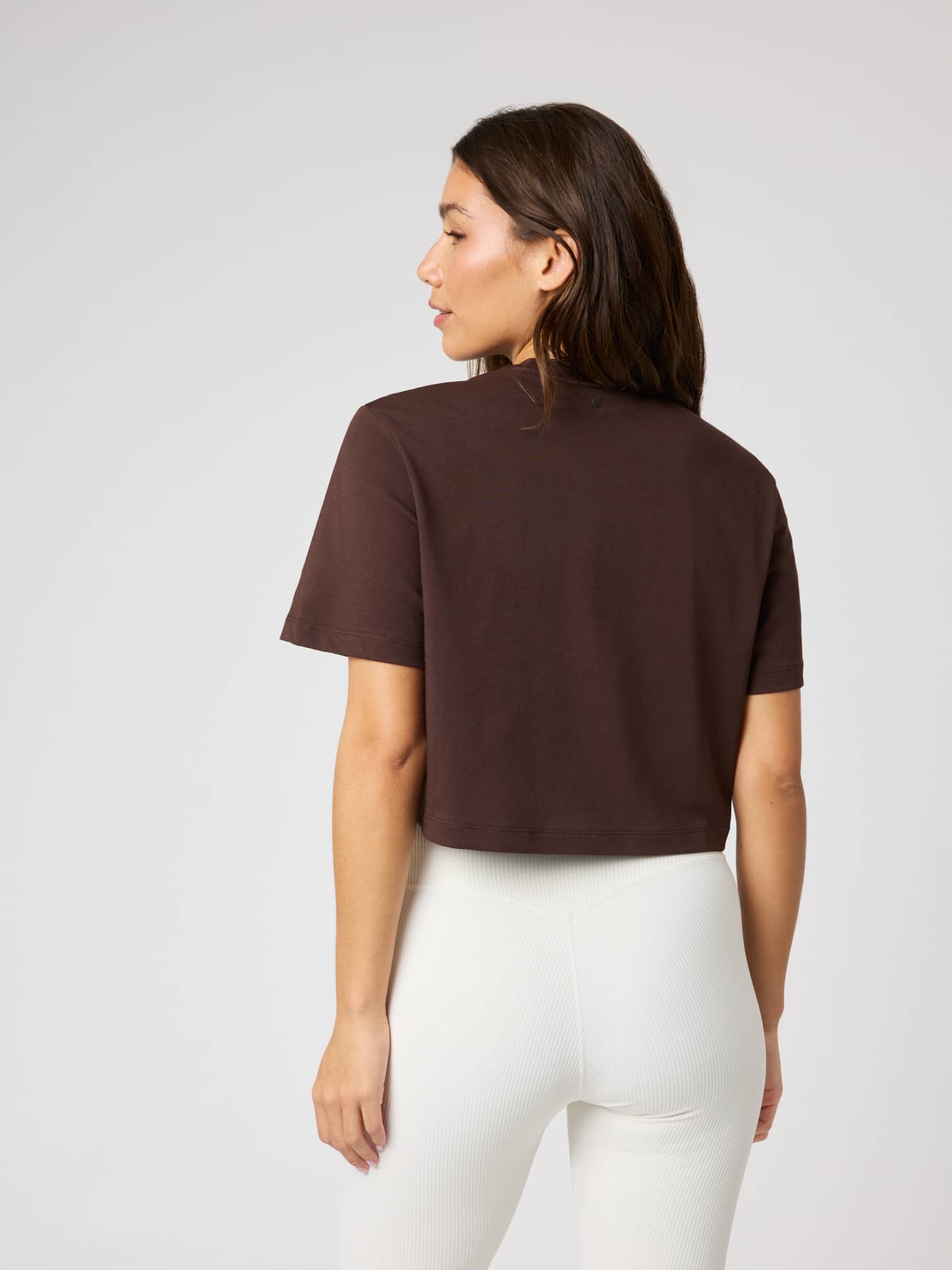 Back view of a model wearing the Studio Oversized Cropped T-Shirt in Coffee Bean (Brown) with a relaxed cotton fit. - Image 2