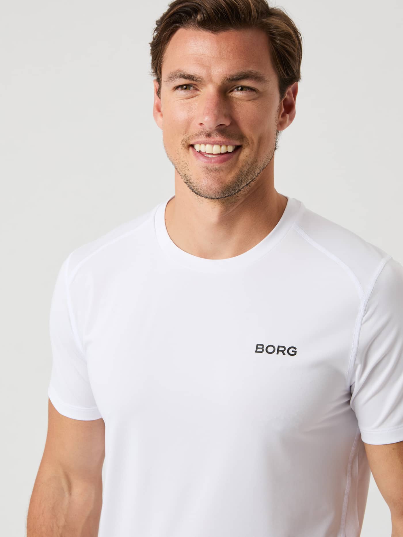 Front view of a man wearing the breathable Borg Airy T-Shirt in Brilliant White (White) with a black chest logo. - Image 4