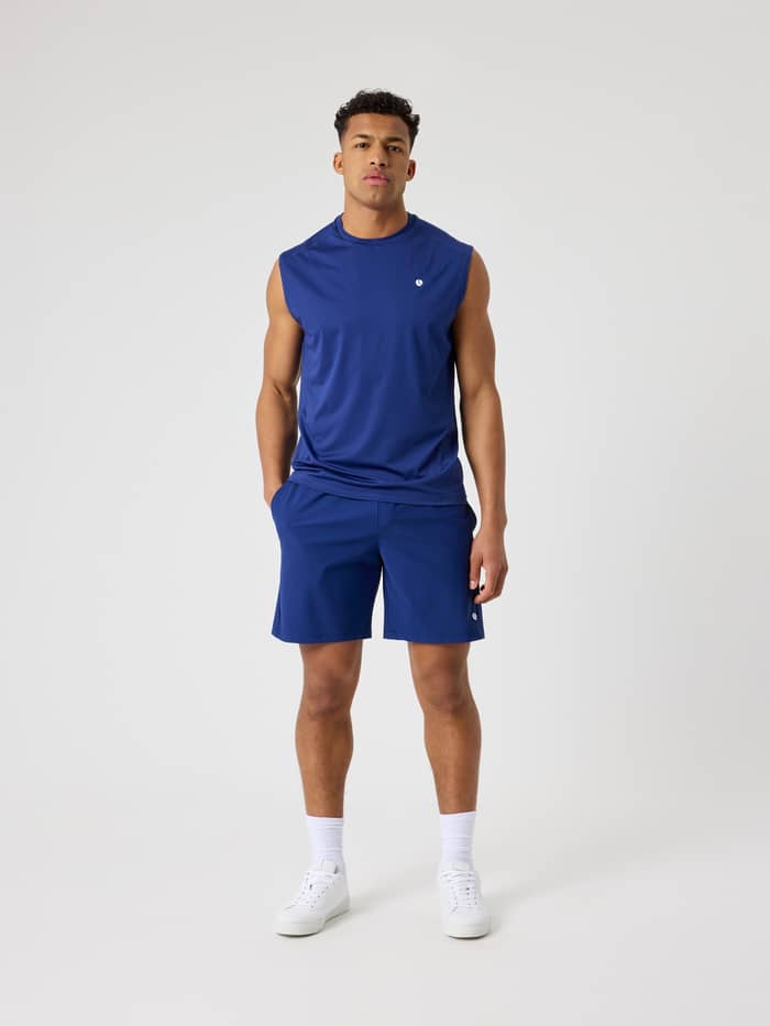 Full-body front view of a man wearing the Blue Depths (Blue) Ace Mesh Panel Tank for tennis and training.