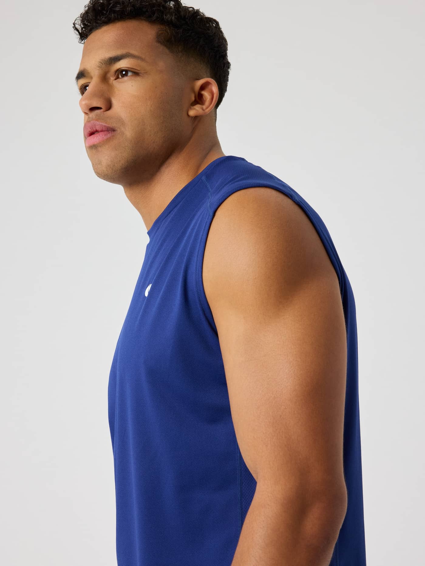 Side view of a man wearing the Björn Borg Ace Mesh Panel Tank in Blue Depths (Blue) with a white logo for tennis. - Image 5