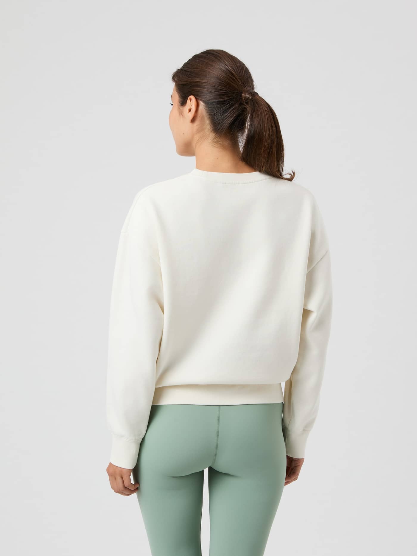 Back view of a woman wearing the oversized Borg Boyfriend Sweatshirt in Cannoli Cream (White) with dropped shoulders. - Image 5