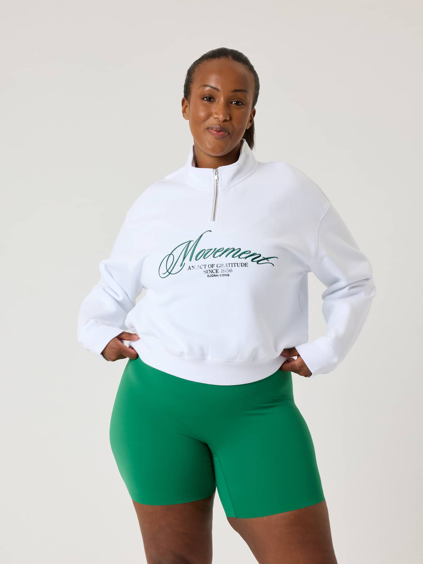 Vue de face d'un mannequin en Alice Stenlöf Halfzip Sweatshirt Brilliant White (Blanc) à coupe régulière avec logo vert. - Image 6