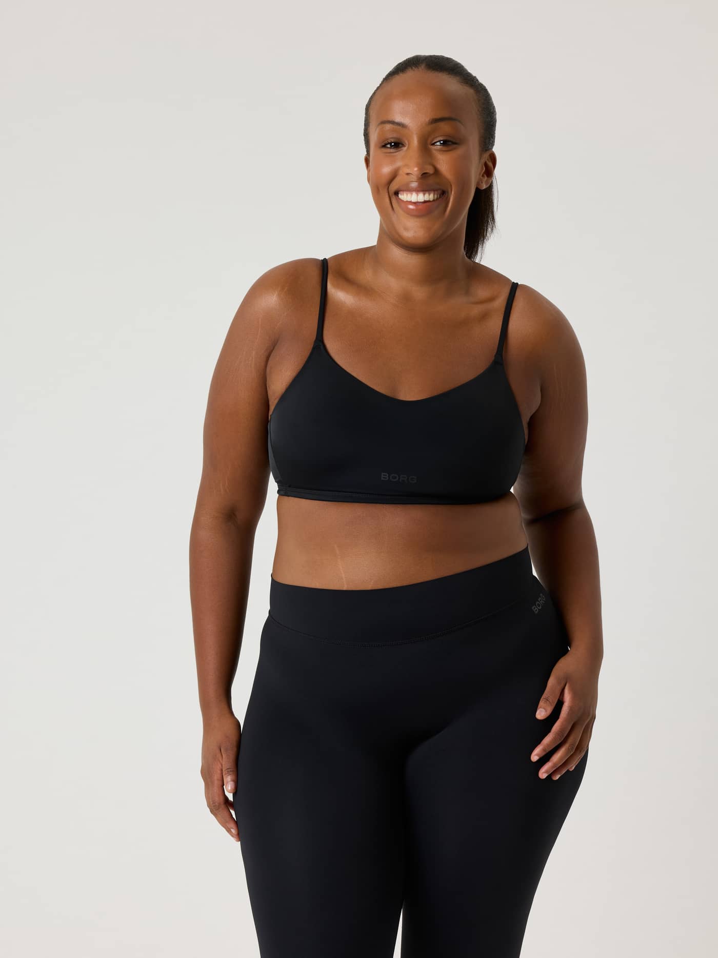 Front view of a model in the black Alice Stenlöf Soft Bra in recycled fabric, with a tonal logo and flexible training fit. - Image 5