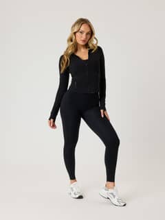 Full-body front view of a woman in the slim-fit Alice Stenlöf Soft Zip Midlayer in Black Beauty (Black) for training. - Image 1